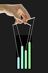 Image showing Businessman keeping the growth in economy, manipulating graphs like puppet