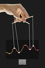 Image showing Businessman keeping the growth in economy, manipulating graphs like puppet