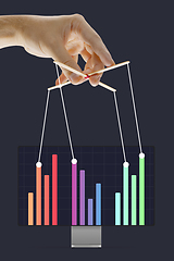 Image showing Businessman keeping the growth in economy, manipulating graphs like puppet