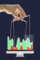 Image showing Businessman keeping the growth in economy, manipulating graphs like puppet