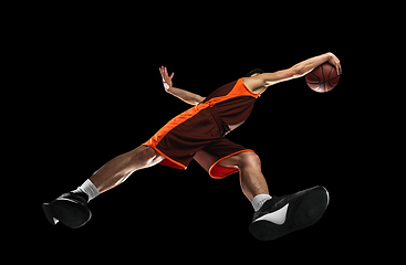 Image showing Young professional basketball player in action, motion isolated on black background, look from the bottom. Concept of sport, movement, energy and dynamic.