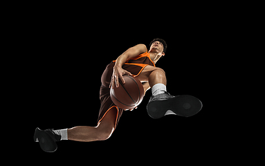 Image showing Young professional basketball player in action, motion isolated on black background, look from the bottom. Concept of sport, movement, energy and dynamic.