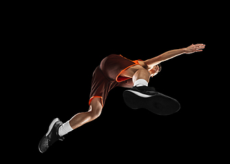 Image showing Young professional basketball player in action, motion isolated on black background, look from the bottom. Concept of sport, movement, energy and dynamic.