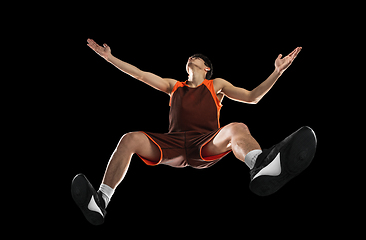 Image showing Young professional basketball player in action, motion isolated on black background, look from the bottom. Concept of sport, movement, energy and dynamic.