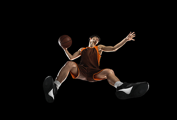 Image showing Young professional basketball player in action, motion isolated on black background, look from the bottom. Concept of sport, movement, energy and dynamic.