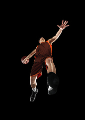 Image showing Young professional basketball player in action, motion isolated on black background, look from the bottom. Concept of sport, movement, energy and dynamic.