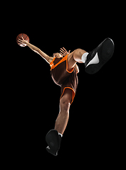 Image showing Young professional basketball player in action, motion isolated on black background, look from the bottom. Concept of sport, movement, energy and dynamic.