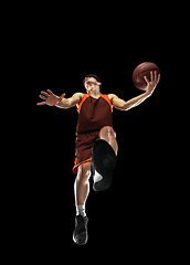 Image showing Young professional basketball player in action, motion isolated on black background, look from the bottom. Concept of sport, movement, energy and dynamic.