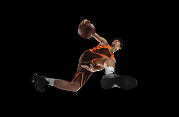 Image showing Young professional basketball player in action, motion isolated on black background, look from the bottom. Concept of sport, movement, energy and dynamic.