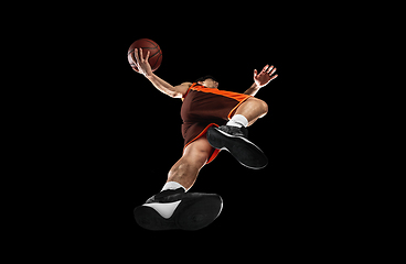 Image showing Young professional basketball player in action, motion isolated on black background, look from the bottom. Concept of sport, movement, energy and dynamic.