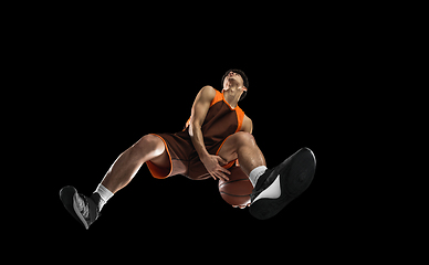 Image showing Young professional basketball player in action, motion isolated on black background, look from the bottom. Concept of sport, movement, energy and dynamic.