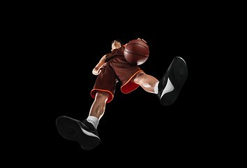 Image showing Young professional basketball player in action, motion isolated on black background, look from the bottom. Concept of sport, movement, energy and dynamic.