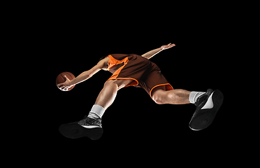 Image showing Young professional basketball player in action, motion isolated on black background, look from the bottom. Concept of sport, movement, energy and dynamic.