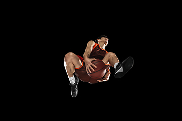 Image showing Young professional basketball player in action, motion isolated on black background, look from the bottom. Concept of sport, movement, energy and dynamic.