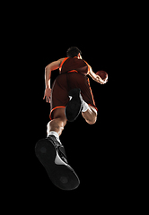 Image showing Young professional basketball player in action, motion isolated on black background, look from the bottom. Concept of sport, movement, energy and dynamic.