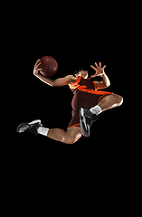 Image showing Young professional basketball player in action, motion isolated on black background, look from the bottom. Concept of sport, movement, energy and dynamic.