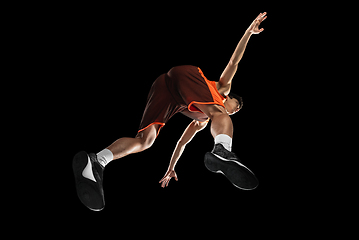 Image showing Young professional basketball player in action, motion isolated on black background, look from the bottom. Concept of sport, movement, energy and dynamic.