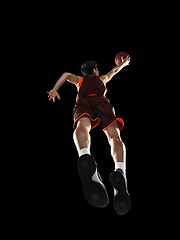 Image showing Young professional basketball player in action, motion isolated on black background, look from the bottom. Concept of sport, movement, energy and dynamic.