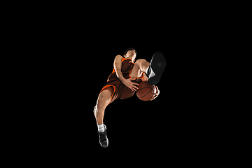 Image showing Young professional basketball player in action, motion isolated on black background, look from the bottom. Concept of sport, movement, energy and dynamic.