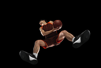 Image showing Young professional basketball player in action, motion isolated on black background, look from the bottom. Concept of sport, movement, energy and dynamic.