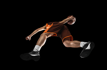 Image showing Young professional basketball player in action, motion isolated on black background, look from the bottom. Concept of sport, movement, energy and dynamic.