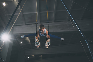 Image showing Little male gymnast training in gym, flexible and active. Caucasian fit little boy, athlete in sportswear practicing in exercises for strength, balance.