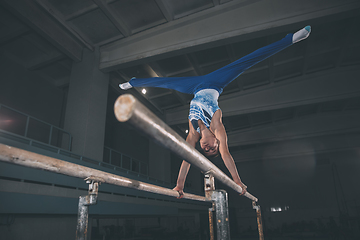 Image showing Little male gymnast training in gym, flexible and active. Caucasian fit little boy, athlete in sportswear practicing in exercises for strength, balance.