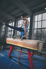 Image showing Little male gymnast training in gym, flexible and active. Caucasian fit little boy, athlete in sportswear practicing in exercises for strength, balance.