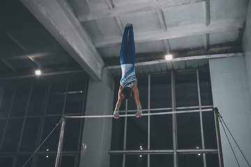 Image showing Little male gymnast training in gym, flexible and active. Caucasian fit little boy, athlete in sportswear practicing in exercises for strength, balance.