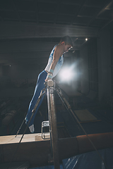 Image showing Little male gymnast training in gym, flexible and active. Caucasian fit little boy, athlete in sportswear practicing in exercises for strength, balance.