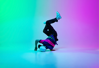 Image showing Beautiful sportive boy dancing hip-hop in stylish clothes on colorful gradient background at dance hall in neon light.