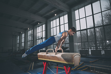 Image showing Little male gymnast training in gym, flexible and active. Caucasian fit little boy, athlete in sportswear practicing in exercises for strength, balance.