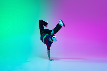 Image showing Beautiful sportive boy dancing hip-hop in stylish clothes on colorful gradient background at dance hall in neon light.