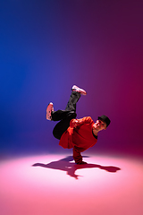 Image showing Beautiful sportive boy dancing hip-hop in stylish clothes on colorful gradient background at dance hall in neon light.