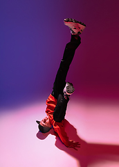 Image showing Beautiful sportive boy dancing hip-hop in stylish clothes on colorful gradient background at dance hall in neon light.