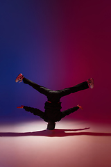 Image showing Beautiful sportive boy dancing hip-hop in stylish clothes on colorful gradient background at dance hall in neon light.