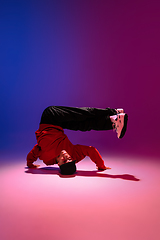 Image showing Beautiful sportive boy dancing hip-hop in stylish clothes on colorful gradient background at dance hall in neon light.