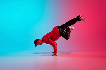 Image showing Beautiful sportive boy dancing hip-hop in stylish clothes on colorful gradient background at dance hall in neon light.