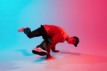 Image showing Beautiful sportive boy dancing hip-hop in stylish clothes on colorful gradient background at dance hall in neon light.