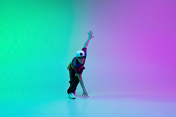 Image showing Beautiful sportive boy dancing hip-hop in stylish clothes on colorful gradient background at dance hall in neon light.