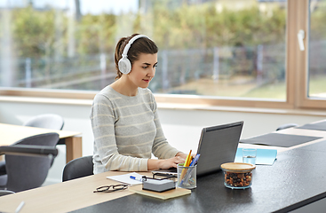 Image showing woman in headphones with laptop working at home