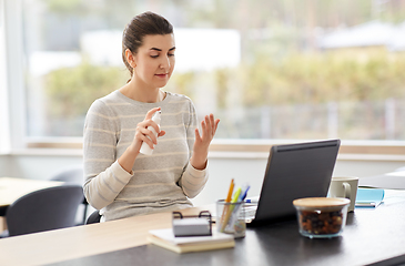 Image showing woman spraying hand sanitizer at home office