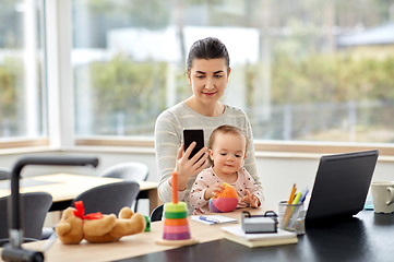 Image showing mother with baby and phone working at home office