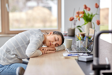 Image showing tired woman sleeping on table with laptop at home