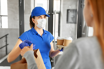 Image showing delivery girl in mask giving paper bag to customer