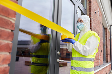 Image showing healthcare worker sealing door with caution tape