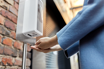 Image showing close up of woman at dispenser with hand sanitizer