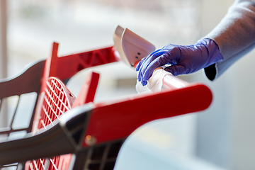 Image showing hand cleaning shopping cart handle with wet wipe