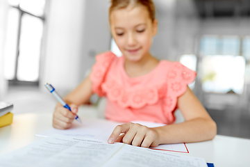 Image showing student girl with book writing to notebook at home