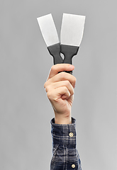 Image showing close up of builder's hand holding putty knives